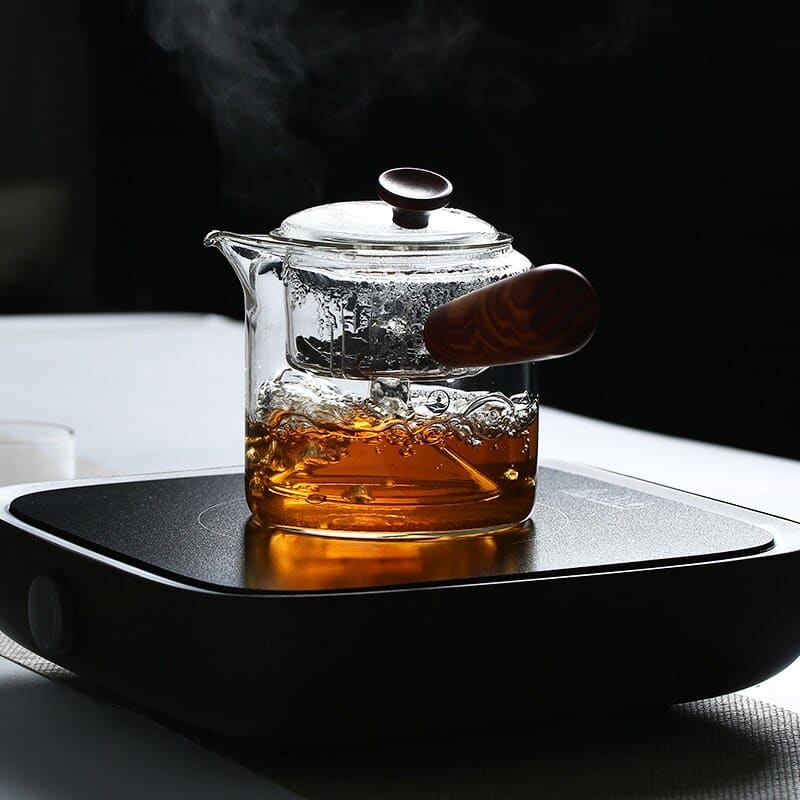 Japanische teekanne aus glas mit holzgriff an der seite